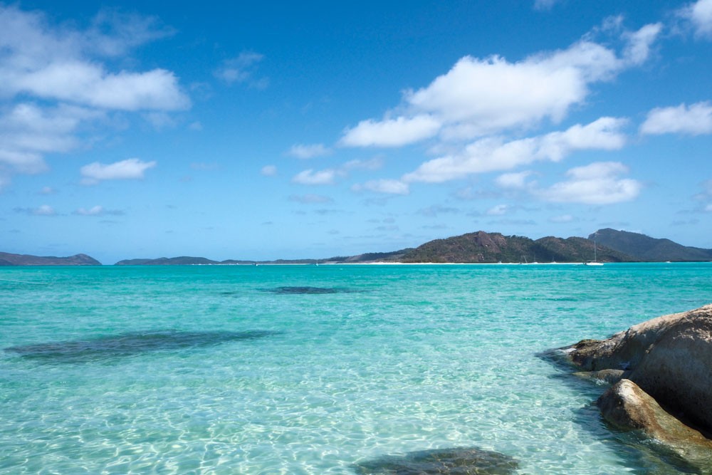 fotografía de una playa de las islas de Australia llamadas Whitsundays. Aparece el bar y de fonod las montaás de las islas